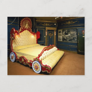 Tufted sleigh bed with wheels and a peacock postcard