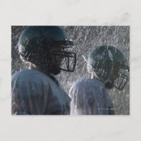 Two American football players in rain, side view