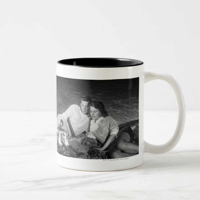 Two couples on beach sitting around campfire Two-Tone coffee mug (Right)