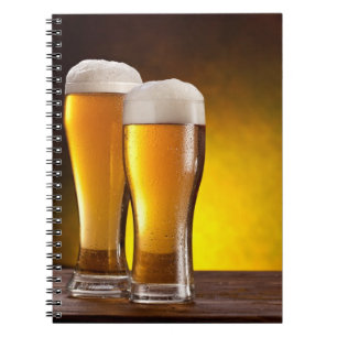Two glasses of beers on a wooden table notebook