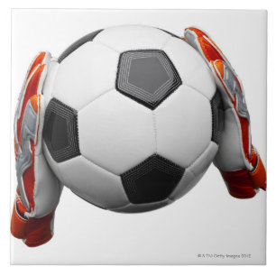 Two goal keepers gloves holding a football ceramic tile
