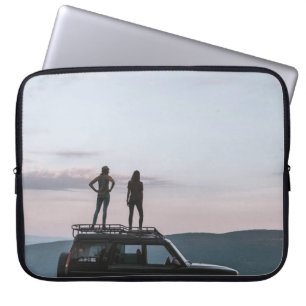 Two women standing on car's roof laptop sleeve