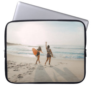 Two women walking towards the ocean carrying surfb laptop sleeve
