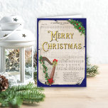 Vintage Christmas Sheet Music Harp Holiday Card<br><div class="desc">This traditional Merry Christmas card features a vintage sheet music Christmas carol scroll behind a harp decorated with festive holly leaves and berries. The holiday Christmas design has a dark blue metallic background. Merry Christmas is in decorative gold lettering on the front,  and a holiday message is inside.</div>