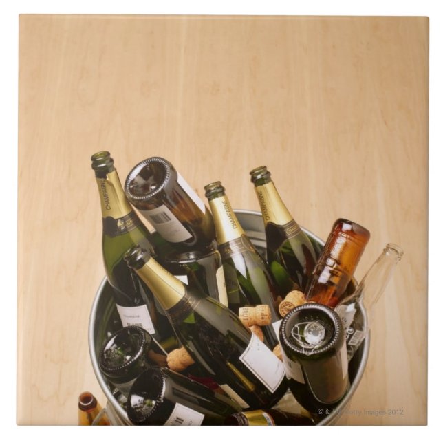 Waste bin full of empty champagne bottles on ceramic tile (Front)