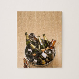 Waste bin full of empty champagne bottles on jigsaw puzzle