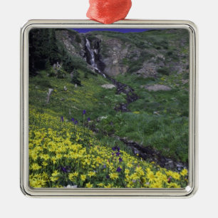 Waterfall and wildflowers in alpine meadow, metal tree decoration