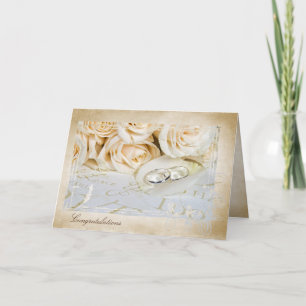 wedding rings on rose petal congratulations card