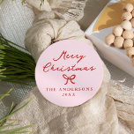 Whimsical Hand-Drawn Bow Pink Christmas Classic Round Sticker<br><div class="desc">Add a playful twist to your holiday packaging with these Christmas stickers featuring “Merry Christmas” in handwritten red script on a blush pink background. A hand-drawn red bow separates the greeting from your name and year, creating a cheerful, whimsical design. Great for sealing Christmas card envelopes, labelling holiday party favours,...</div>