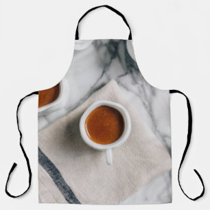 WHITE CERAMIC TEACUP FILLED WITH RED LIQUID APRON