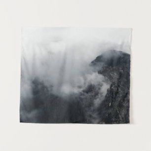White clouds over the dark rocky mountains tapestry