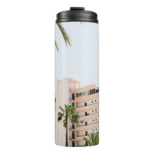 WHITE CONCRETE BUILDING BESIDE GREEN PALM TREE UND THERMAL TUMBLER