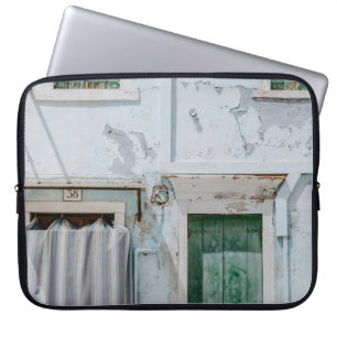 WHITE CONCRETE BUILDING WITH THREE GREEN WINDOWS A LAPTOP SLEEVE