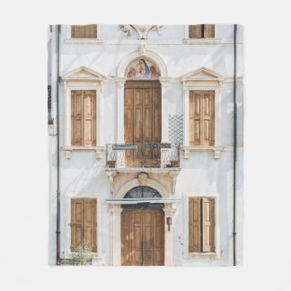 WHITE CONCRETE BUILDING WITH WOODEN DOORS AND WIND FLEECE BLANKET