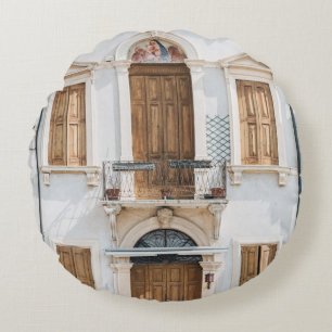 WHITE CONCRETE BUILDING WITH WOODEN DOORS AND WIND ROUND CUSHION