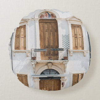 WHITE CONCRETE BUILDING WITH WOODEN DOORS AND WIND ROUND CUSHION