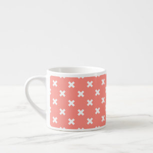 White cross stitches on peach espresso cup