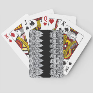 White lace forms a delicate border against black playing cards