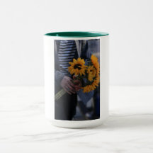 White mug where a hand hold sunflowers with AJ