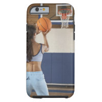 Woman aiming at hoop with basketball, rear view