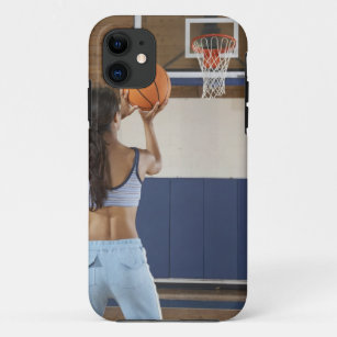 Woman aiming at hoop with basketball, rear view iPhone 11 case