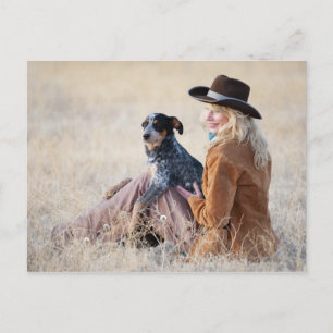 Woman and dog sitting in field postcard