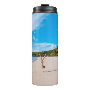 Woman doing acrobatic on seashore near mountain ra thermal tumbler
