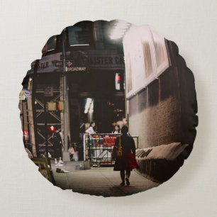 WOMAN IN BLACK AND RED DRESS WALKING BESIDE BROWN ROUND CUSHION