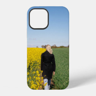 Woman in black coat standing on green grass field iPhone 12 case
