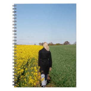 Woman in black coat standing on green grass field notebook