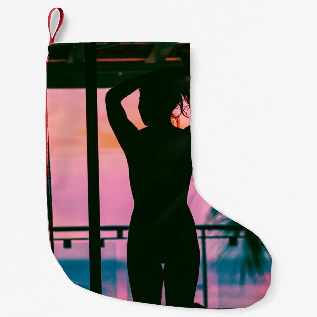 Woman in black tank top and pants standing on blac small christmas stocking (Front)