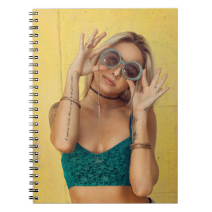 Woman in blue bralette holding sunglasses putting  notebook