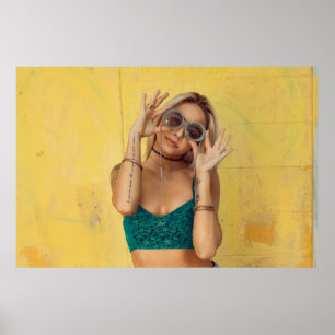 Woman in blue bralette holding sunglasses putting poster