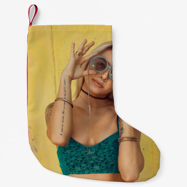 Woman in blue bralette holding sunglasses putting  small christmas stocking (Front)