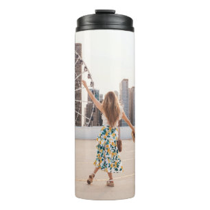 Woman in white and blue floral dress holding hat thermal tumbler