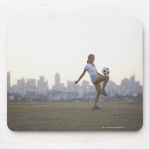 Woman kneeing soccer ball in urban park mouse pad