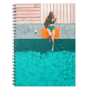 Woman lying beside swimming pool in the morning notebook