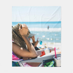 Woman lying on sun lounger covering her face with fleece blanket