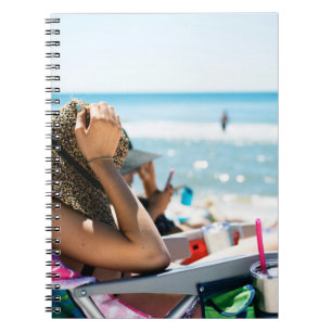 Woman lying on sun lounger covering her face with  notebook