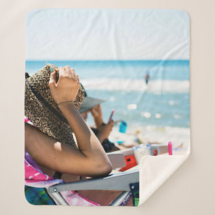 Woman lying on sun lounger covering her face with sherpa blanket