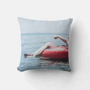Woman on an inflatable float in the ocean pointing cushion