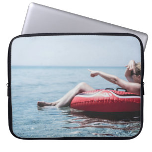 Woman on an inflatable float in the ocean pointing laptop sleeve