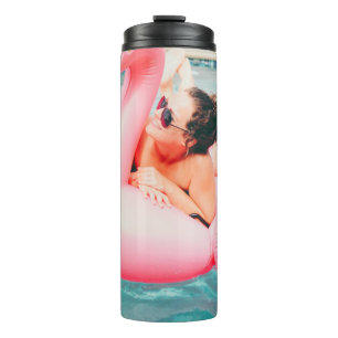 Woman on pink inflatable flamingo on outdoor pool thermal tumbler