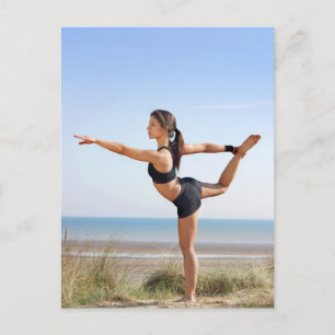 Woman practicing yoga on beach postcard