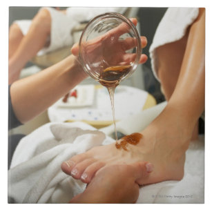 Woman receiving foot massage with oil tile