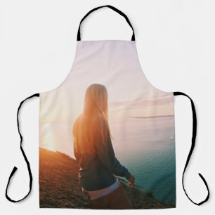 Woman stands near body of water during golden hour apron