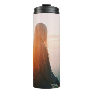 Woman stands near body of water during golden hour thermal tumbler