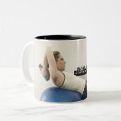 Woman using exercise ball and hand weights Two-Tone coffee mug (Front Left)