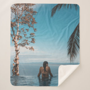 Woman wearing black bikini tap swimming on body of sherpa blanket