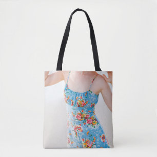 Woman wearing blue floral rompers and brown hat tote bag